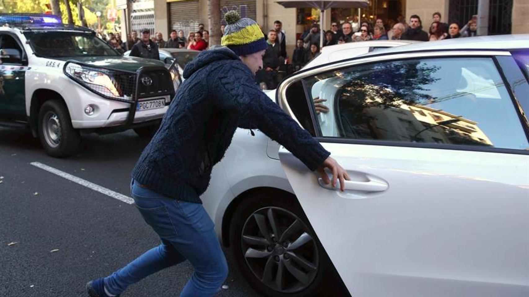 El familiar de uno de los detenidos se abalanza sobre el coche de las fuerzas del orden. Toni Albir / Efe