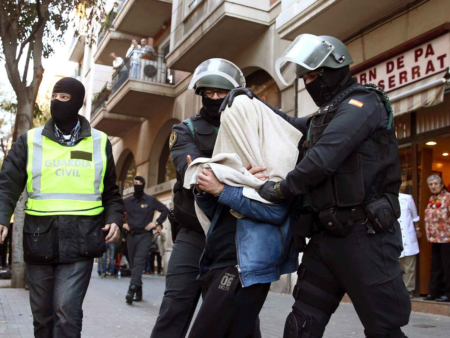 Uno de los tres detenidos sale custodiado por agentes de la benemérita en la calle Marina de Barcelona.
