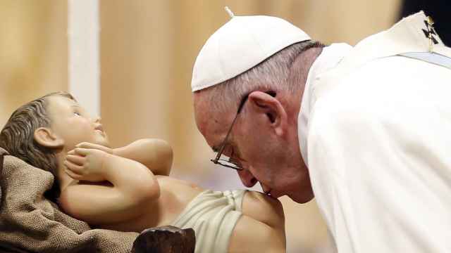 El papa Francisco besa al niño Jesús del belén Vaticano en una misa de Año Nuevo.