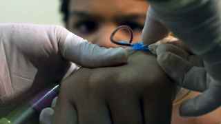 Un sanitario recoge sangre de un niño en busca de la infección.