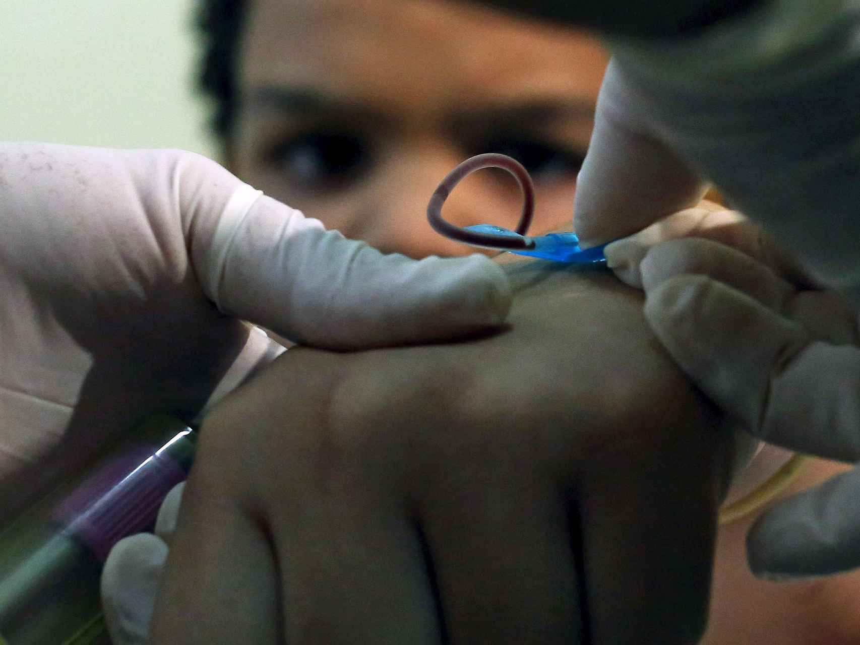 Un sanitario recoge sangre de un niño en busca de la infección.