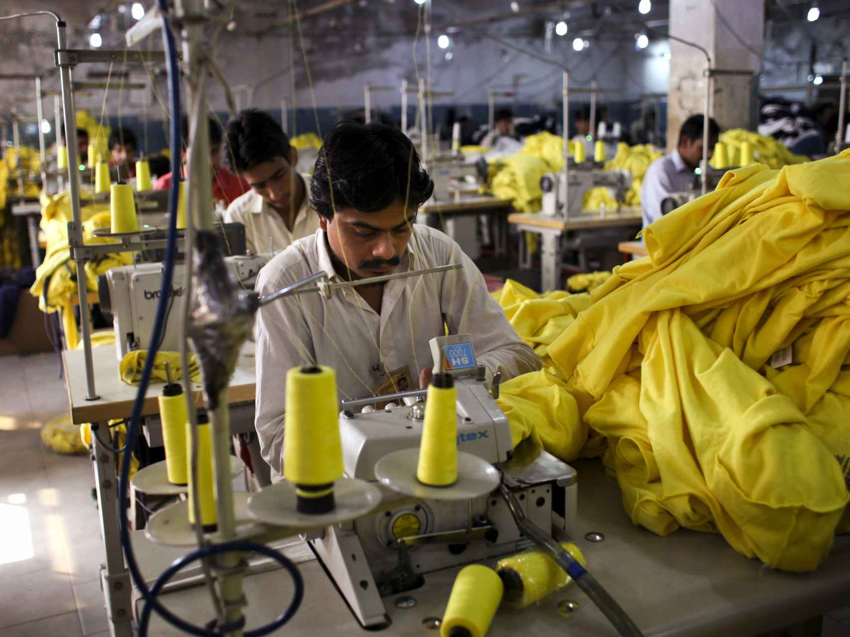 Trabajadores cosen camisetas fabricadas para Inditex en una fábrica en Pakistán.