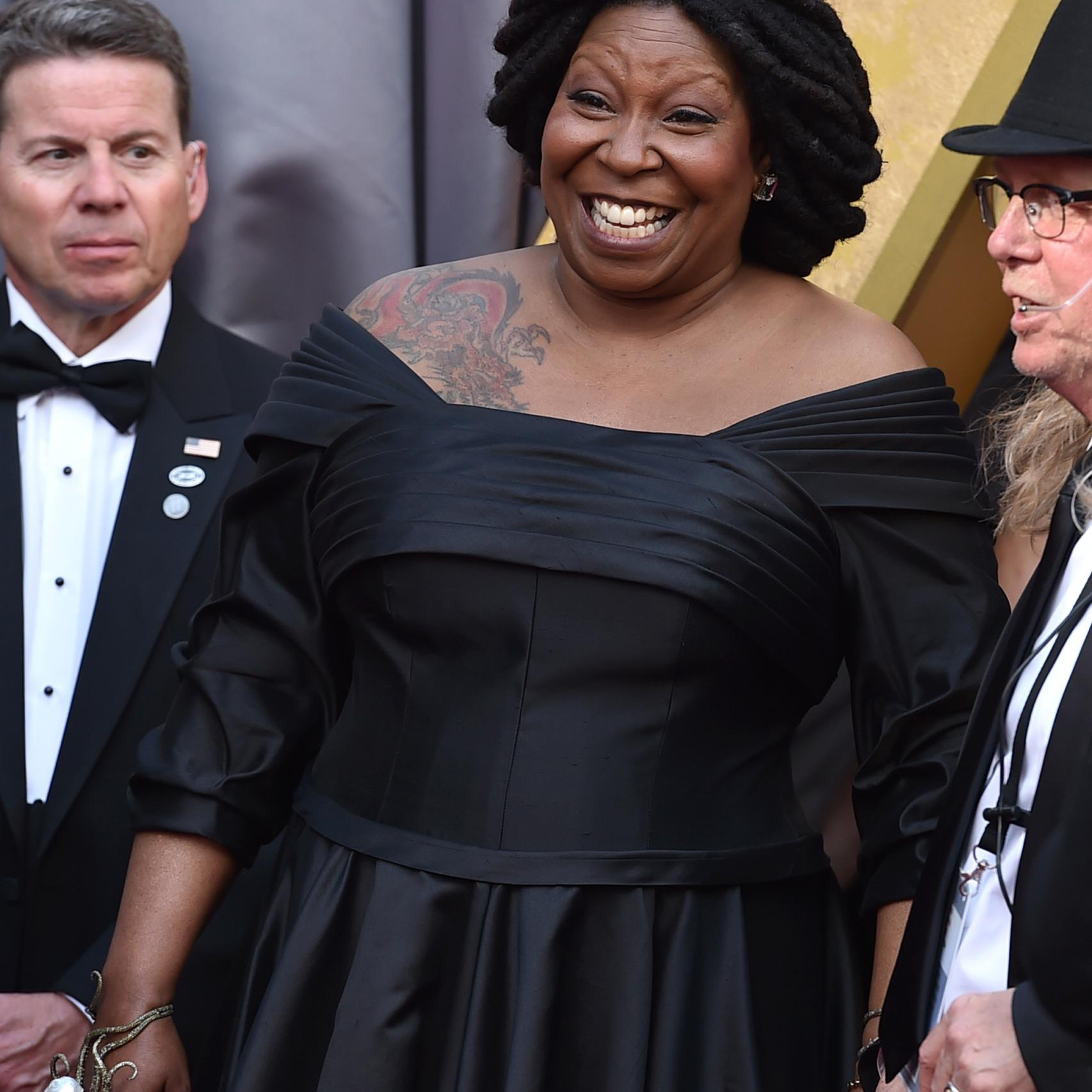 Whoopi Goldberg lleva un vestido negro nada favorecedor. El tatuaje en el hombro anti alfombra roja
