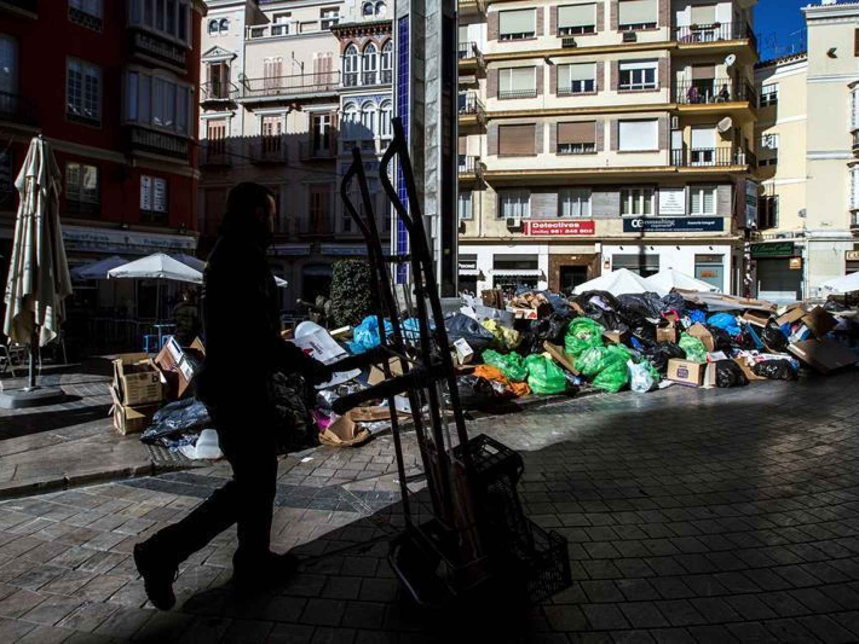Un operario pasa frente a la basura acumulada en las calles de Málaga