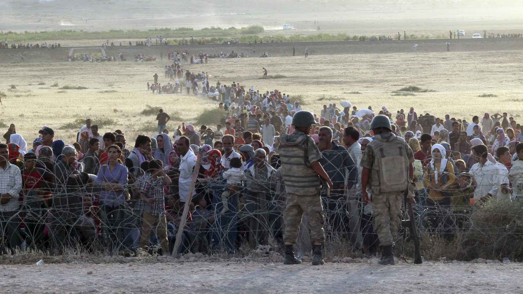 Ciudadanos sirios aguardan junto a la frontera turca.