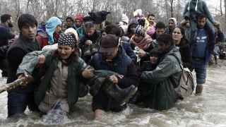 Refugiados en un campamento cerca de Idomeni cruzan un río en la frontera con Macedonia