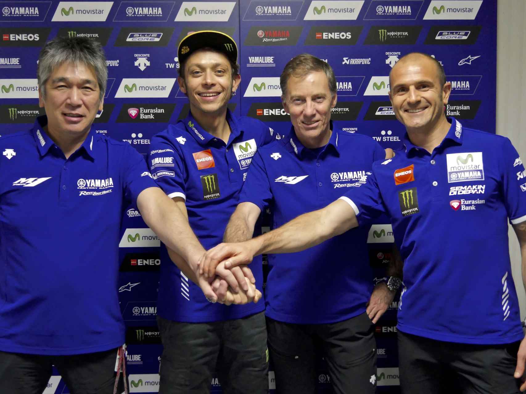 Valentino Rossi une sus manos a las de Lin Jarvis, Massimo Meregalli y Kouichi Tsuji.