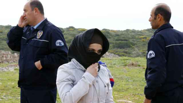 Una mujer siria espera junto a un policía cerca de la ciudad costera turca de Didim.