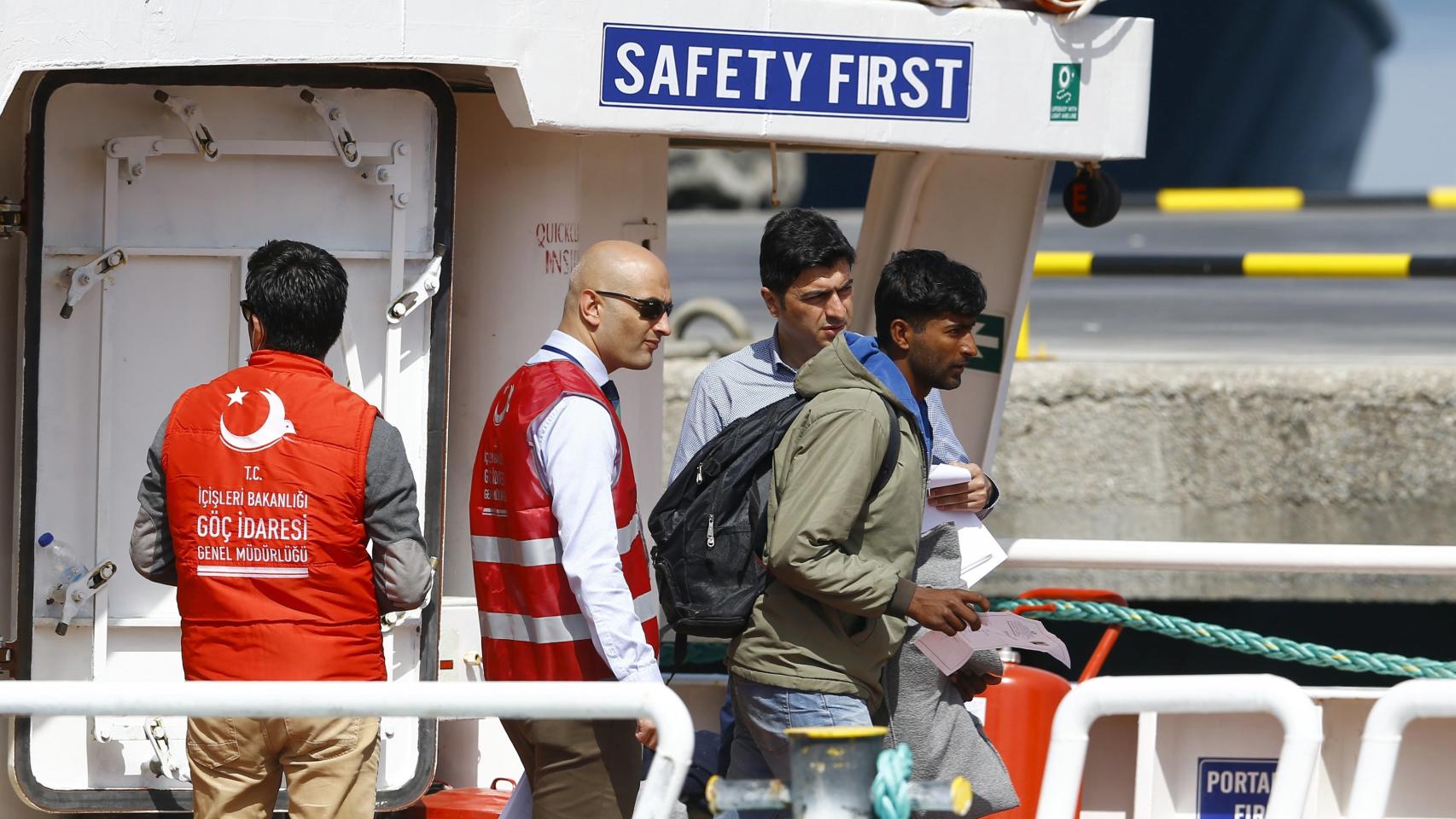 Un migrante deportado a Turquía, bajo una señal de la seguridad, primero.