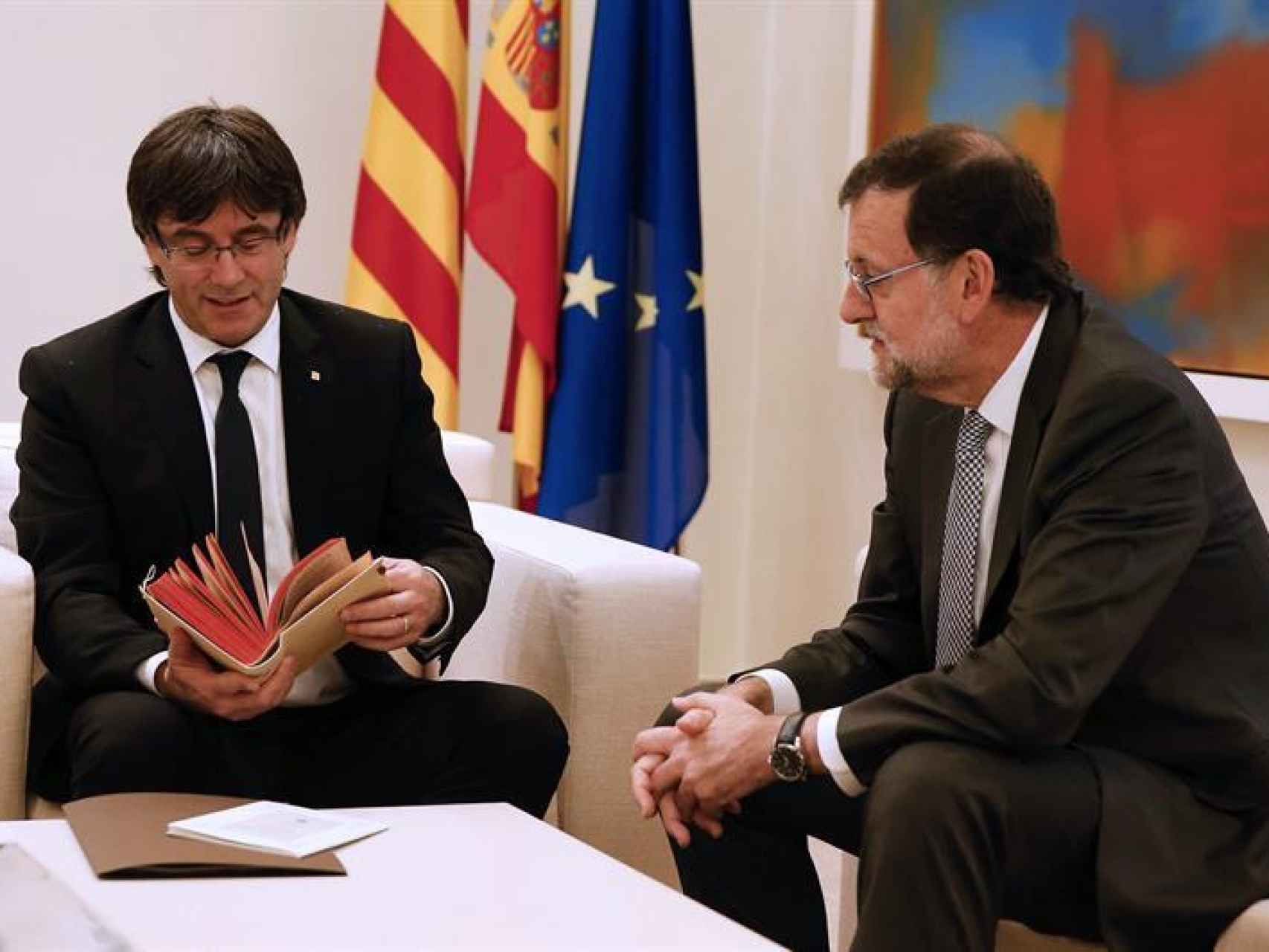 Puigdemont hojeando el regalo de Rajoy.