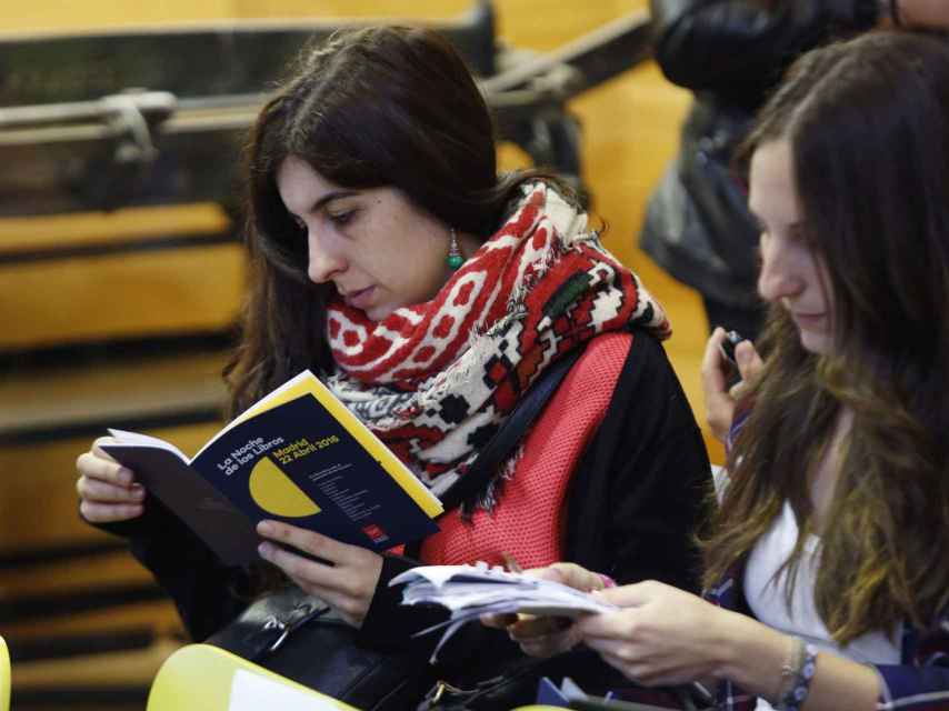 Dos jóvenes leen el programa de la Noche de los libros
