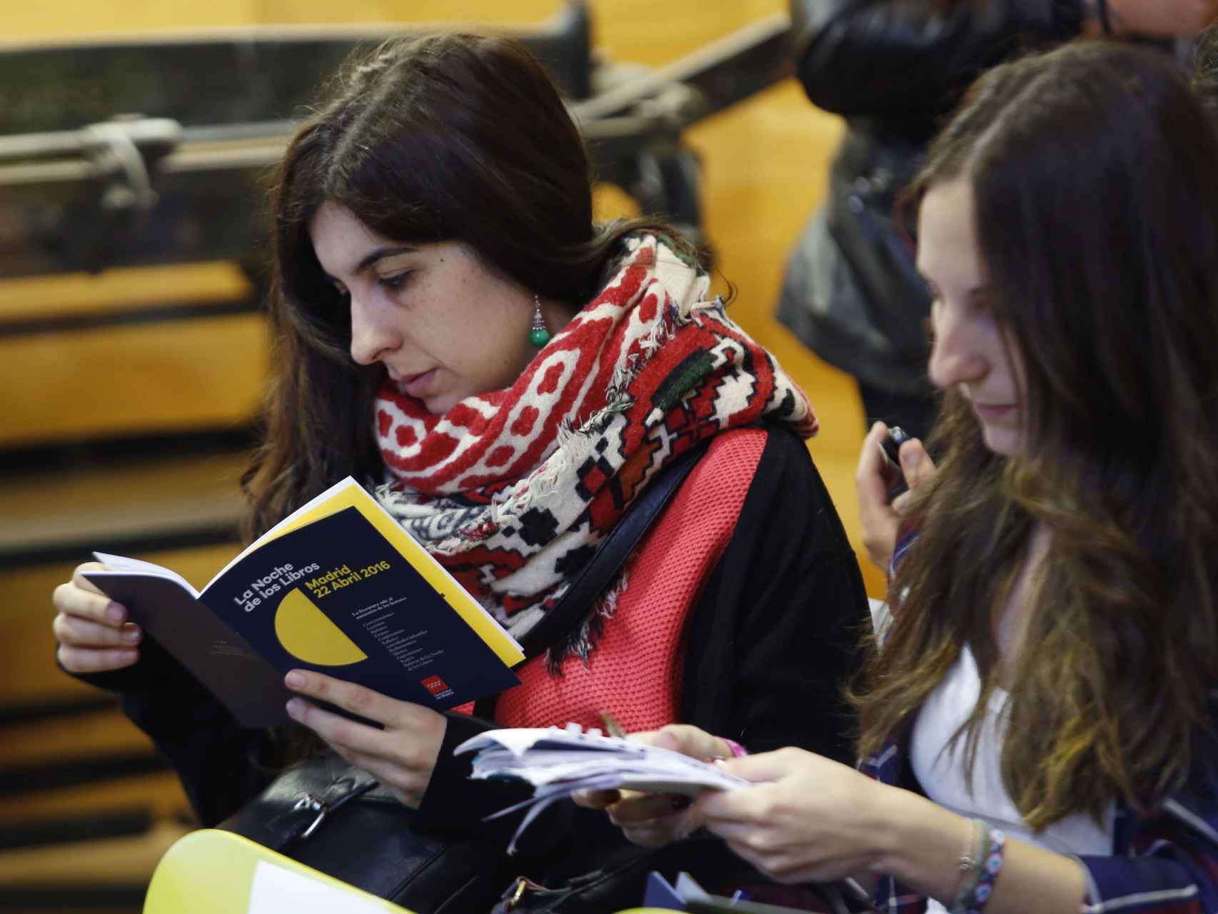 Dos jóvenes leen el programa de la Noche de los libros