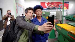 Un periodista extranjero se fotografía con el trabajador de una fábrica durante una visita organizada el 6 de mayo de 2016.