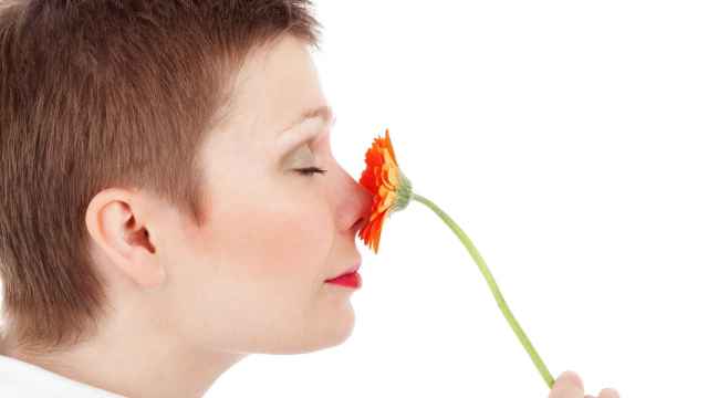 Una mujer huele una flor naranja.