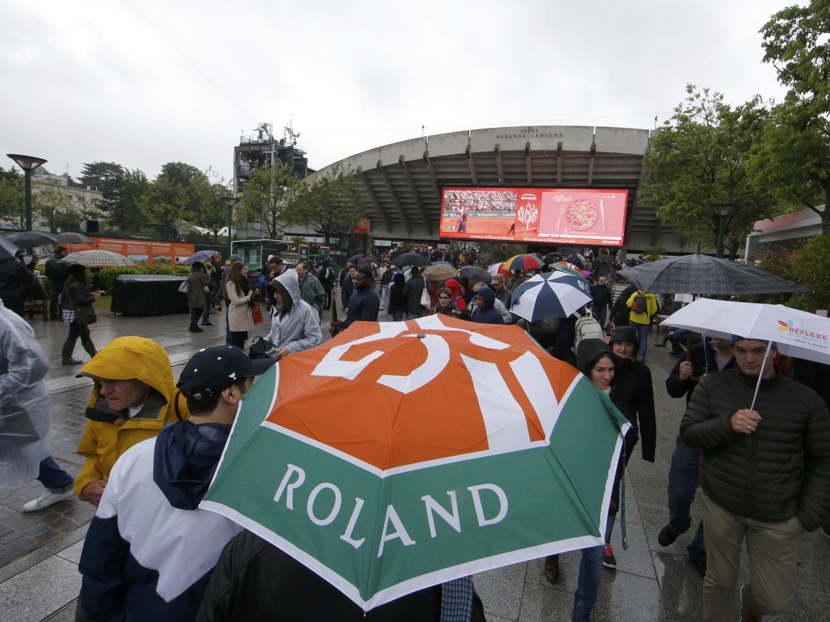 Los aficionados pasan por Roland Garros con paraguas.