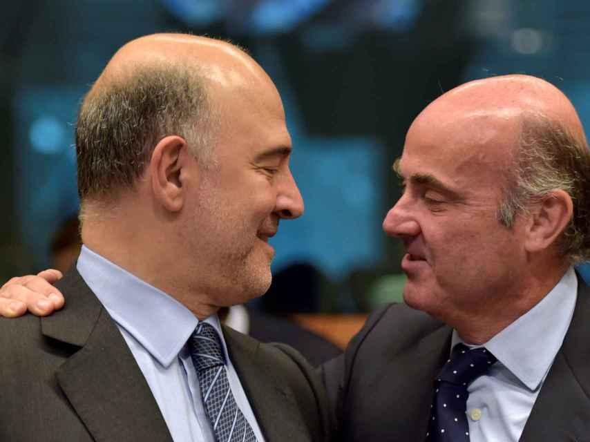 El comisario Moscovici conversa con el ministro Luis de Guindos durante el último Eurogrupo