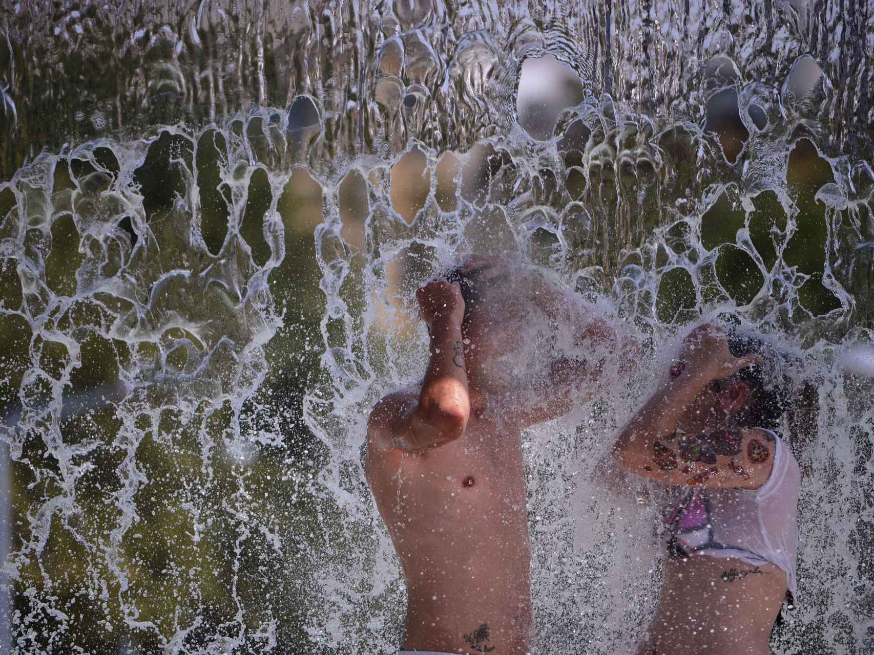Unos jóvenes se bañan en una de las fuentes públicas de la avenida del Libertador en el centro de Córdoba.