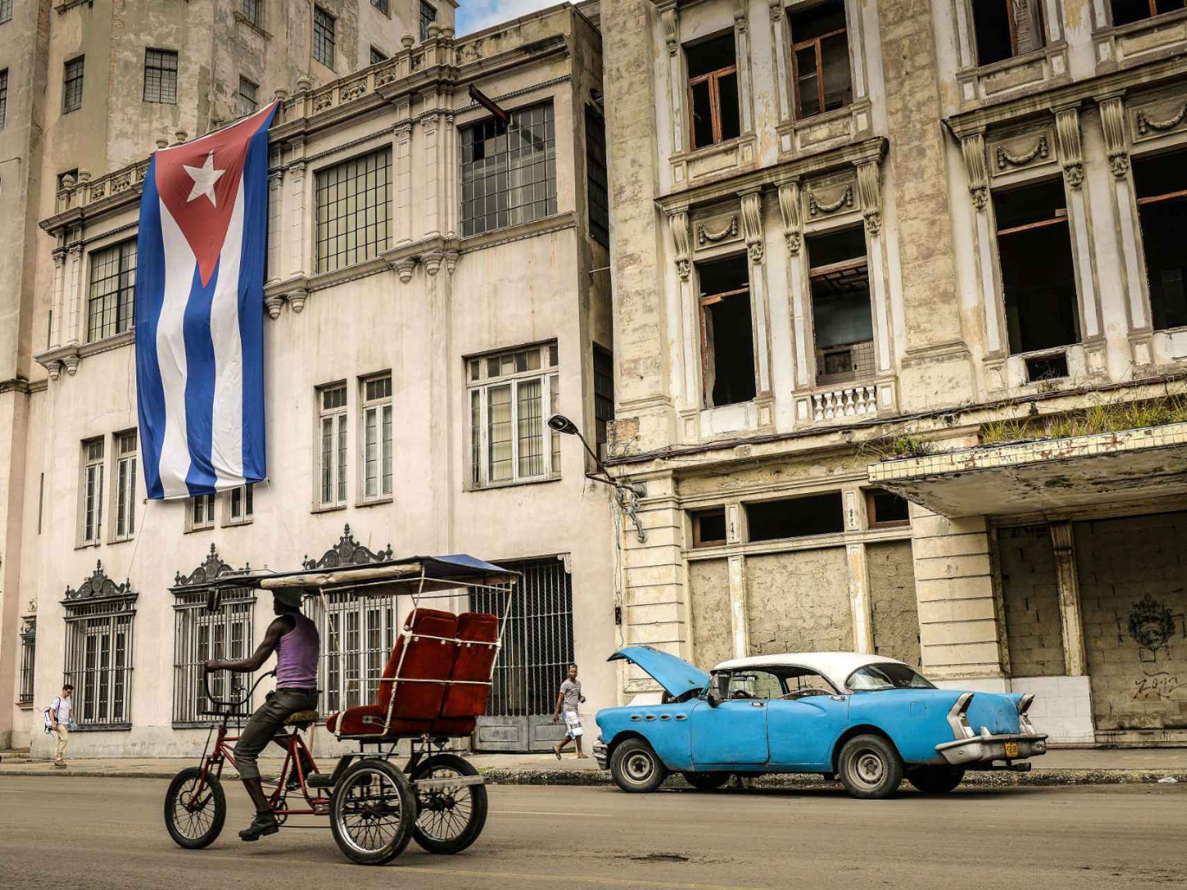 Un hombre conduciendo un bicitaxi en una calle de La Habana.