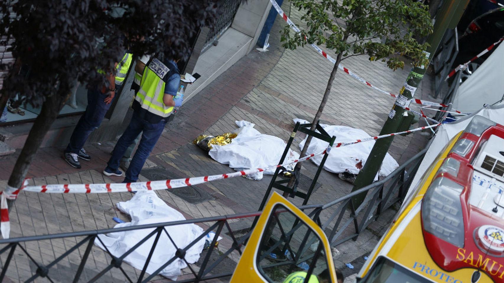 Cadáveres de los fallecidos, junto a agentes de la Policía Científica.