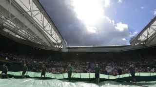 Operarios de Wimbledon cubren la pista central ante la amenaza de lluvia.