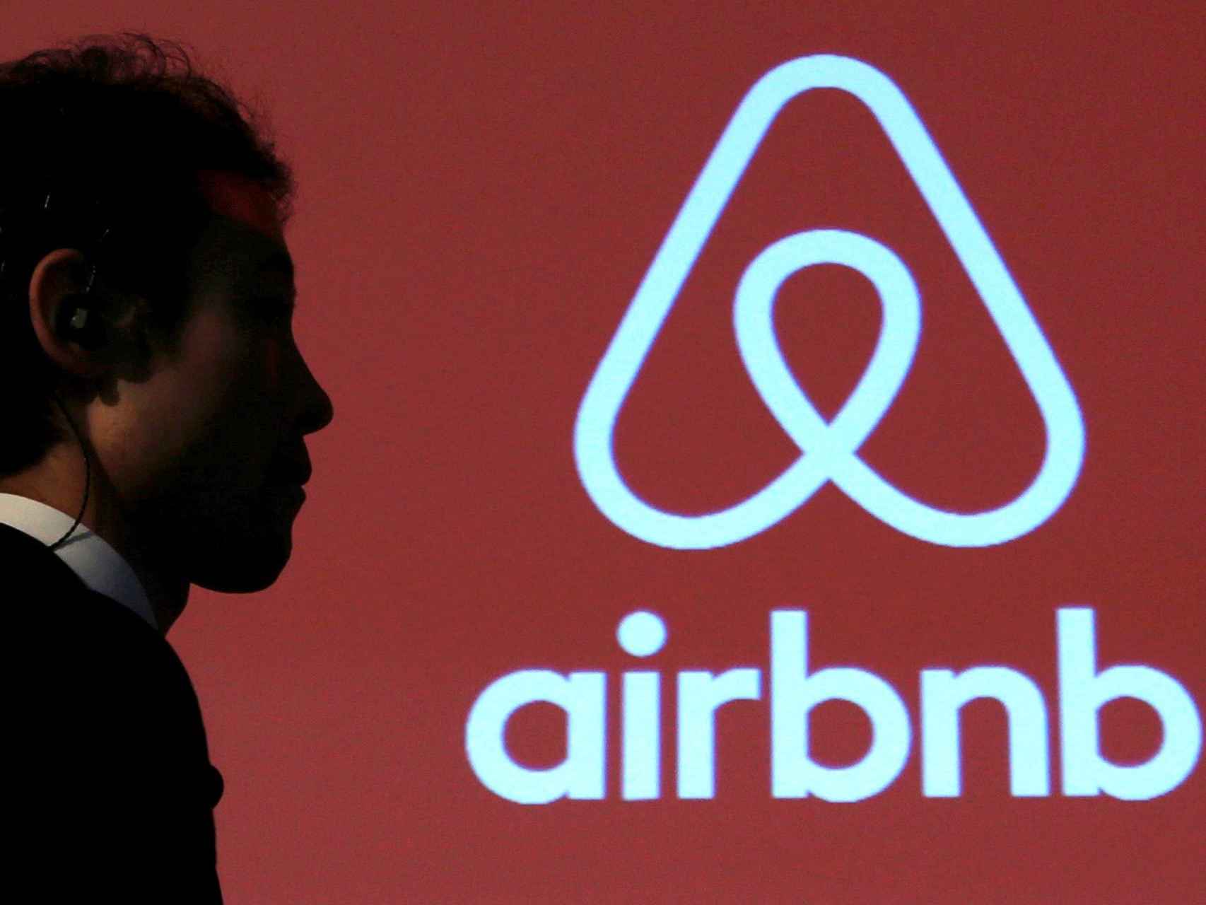 Un hombre pasa por delante del logo de Airbnb.