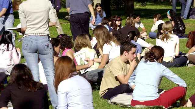 Varios jóvenes estudiantes sentados en un cesped.