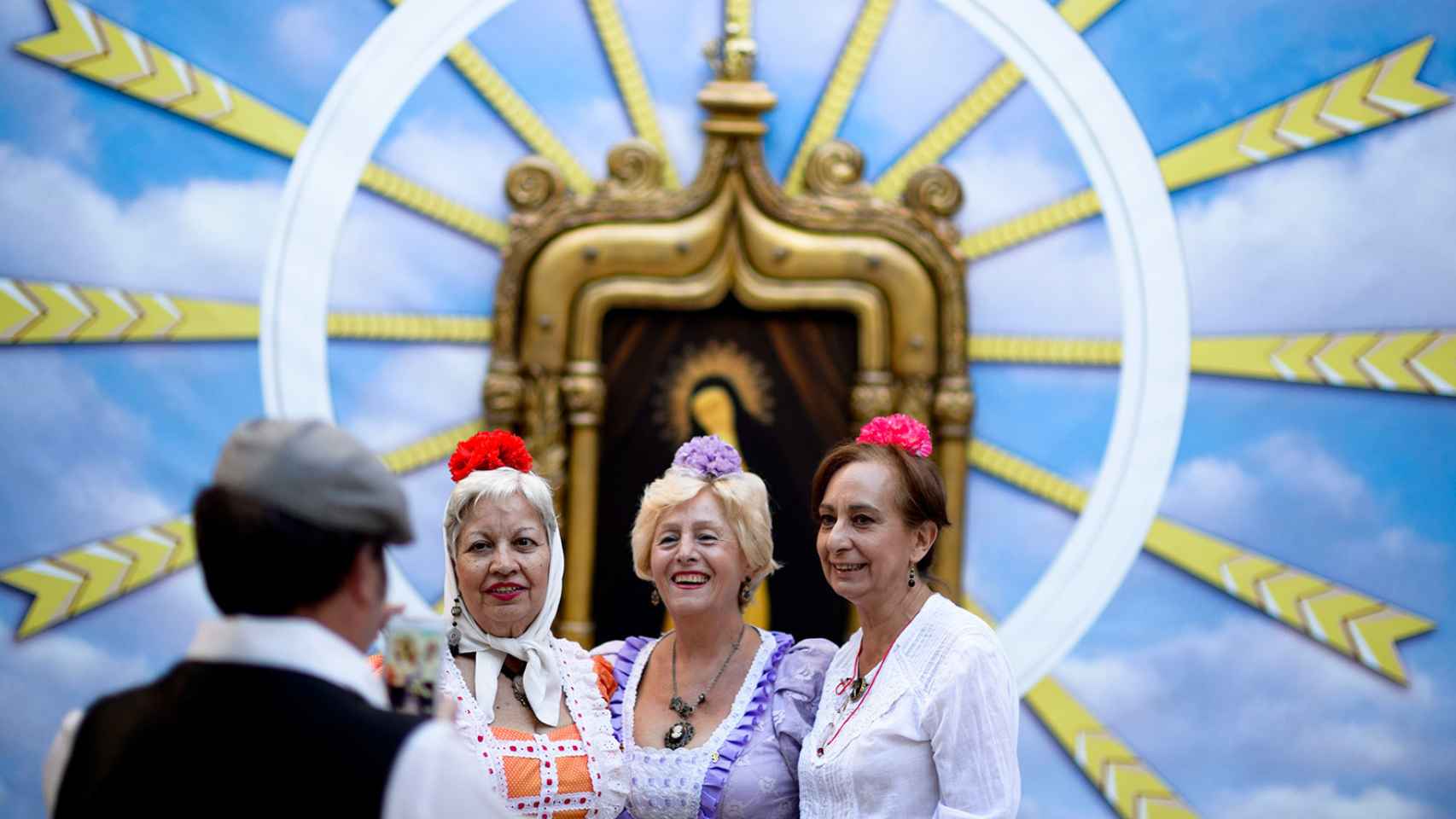Manolas, mujeres vestidas con el traje tradicional, con la Virgen de la Paloma de fondo.