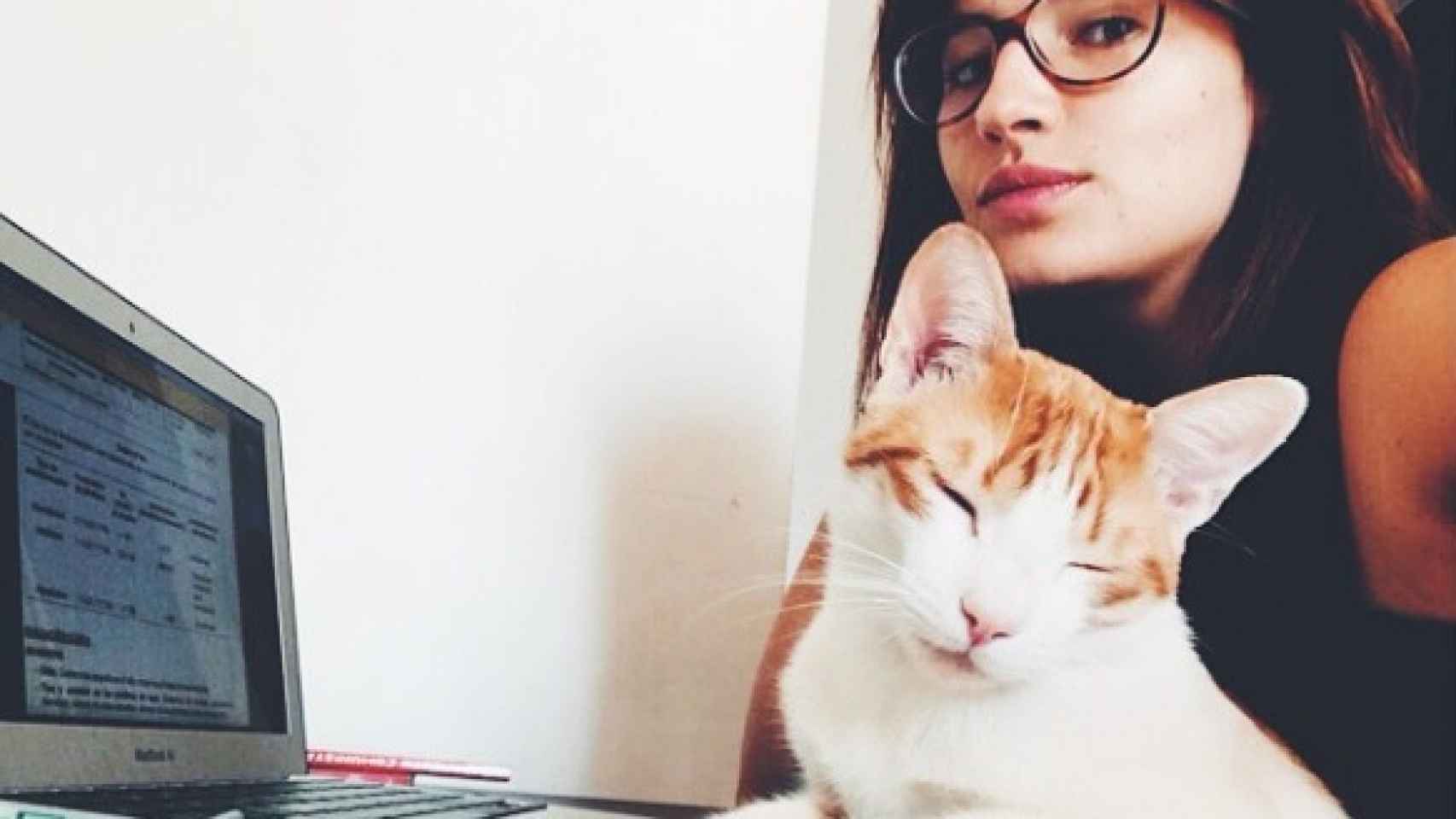 Anna Ruiz y uno de sus gatos frente al ordenador.