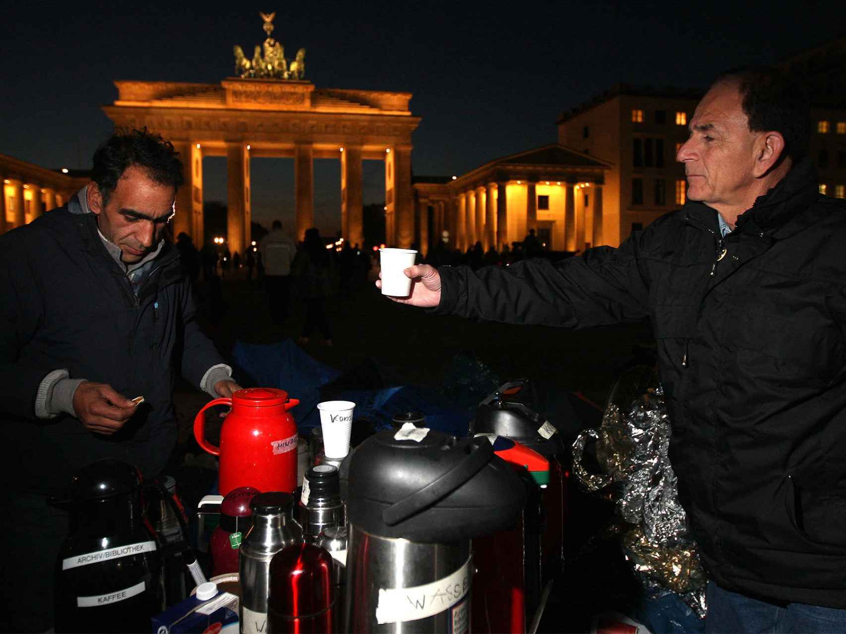 Un voluntario sirve un té a un refugiado en la Puerta de Brandeburgo en Berlín, Alemania.