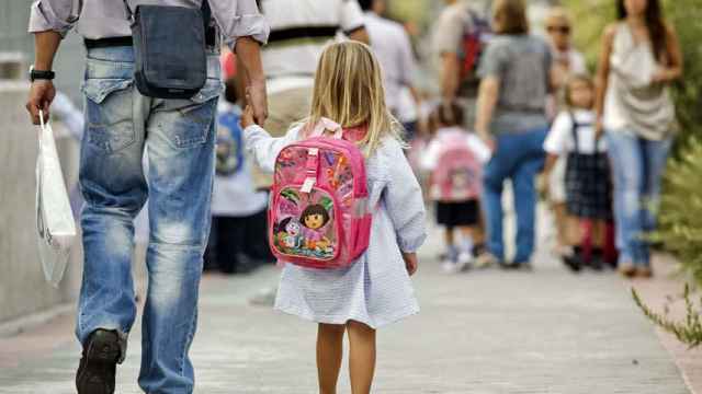 Una niña camina con su padre al colegio.