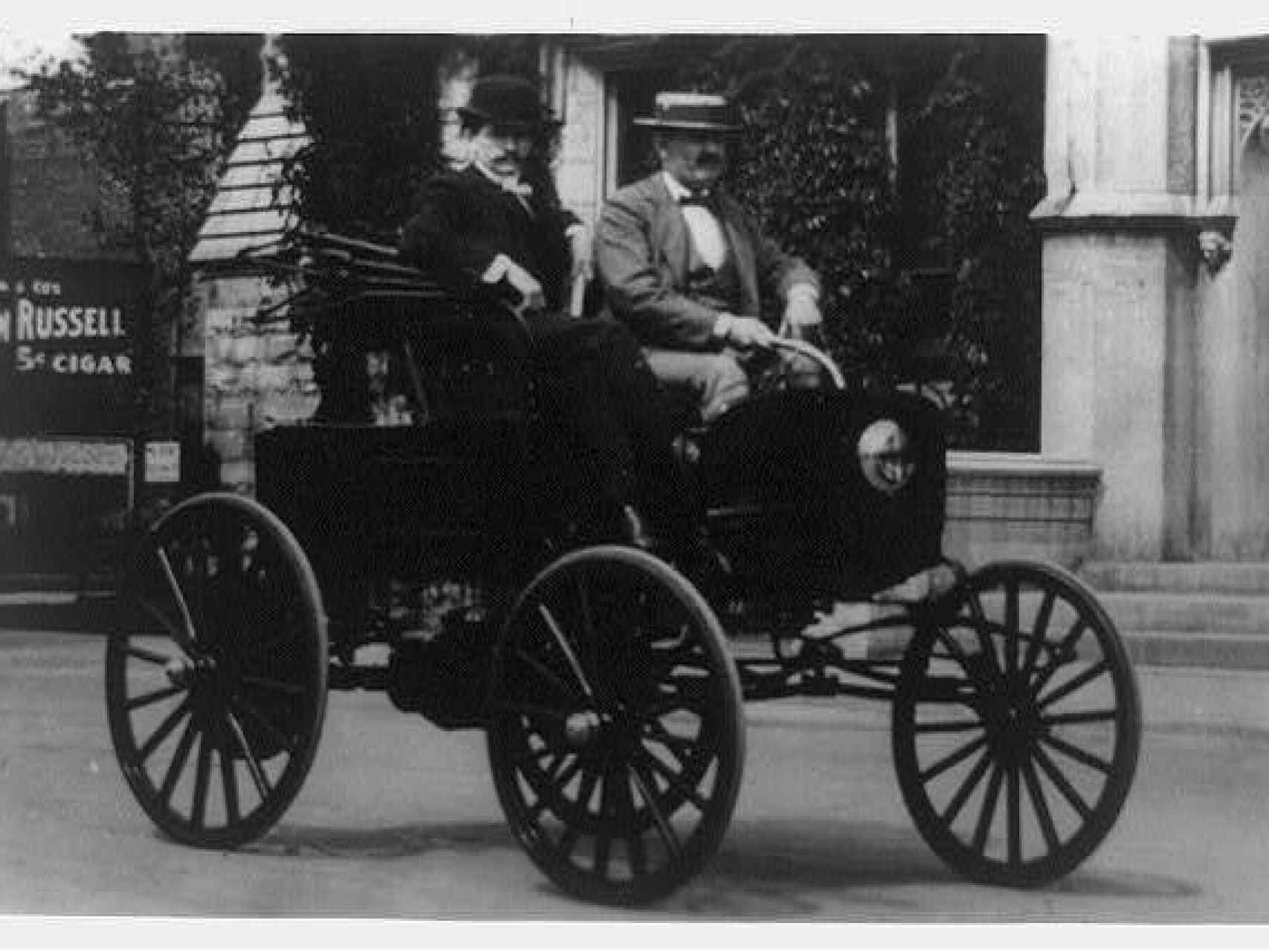 Dos hombres circulando en un vehículo americano de la década de 1890.