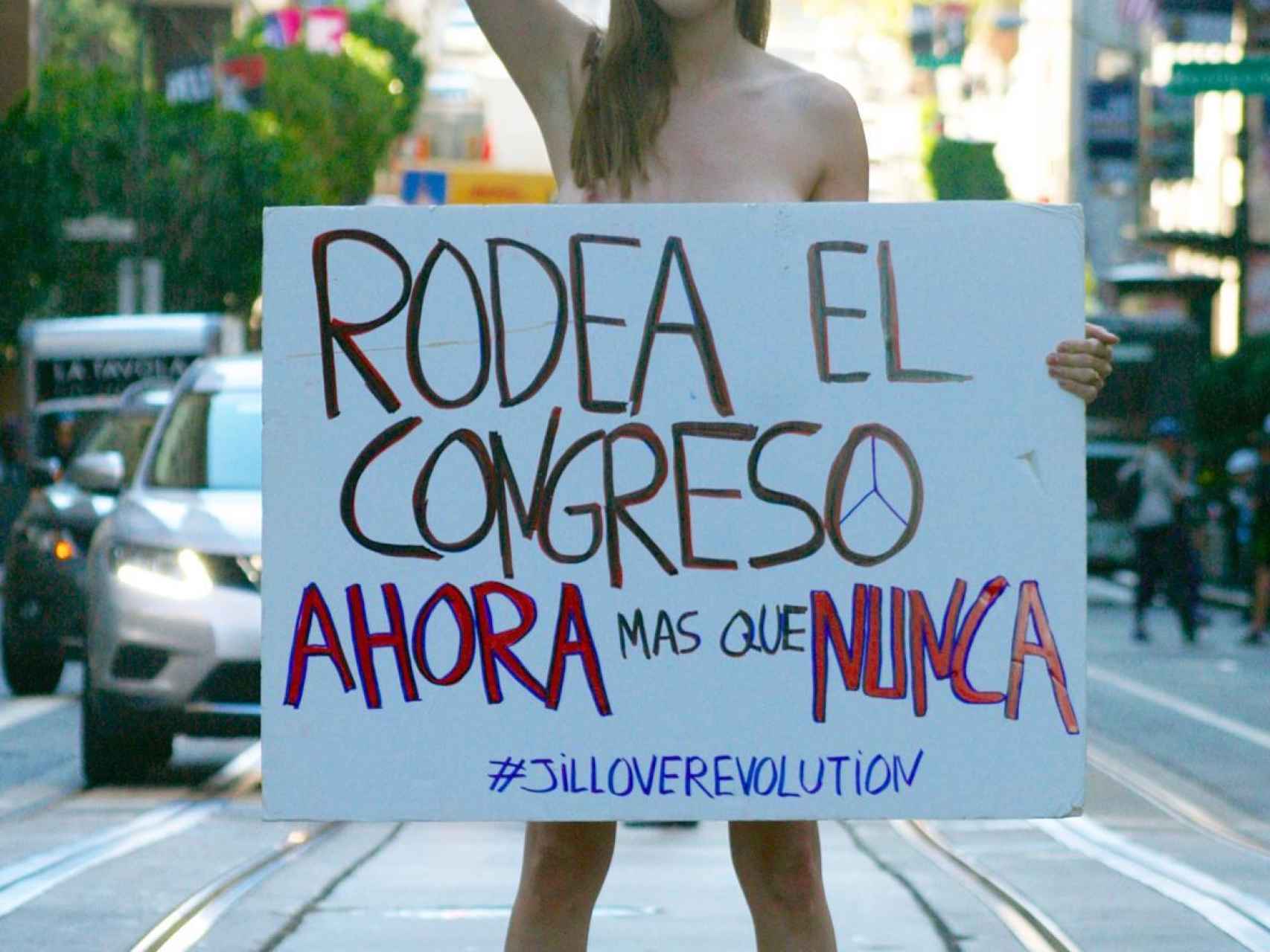 Jil Love posa desde San Francisco para EL ESPAÑOL con una pancarta en la que invita a los ciudadanos a acudir al Rodea el Congreso.