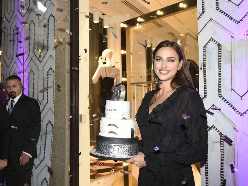 Irina sostiene la tarta y sopló las velas por el 20 aniversario de Intimissimi, con un vestido vaporoso en negro.