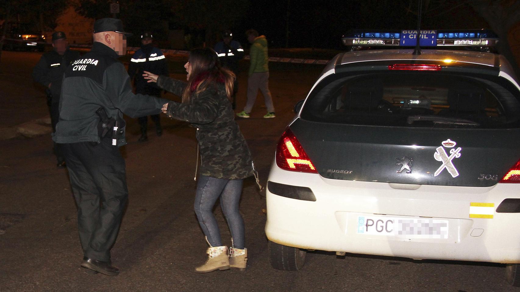 Un guardia civil habla con una mujer cerca de la vienda donde han sido hallados los cadáveres
