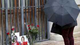 Una persona se para ante unas fotografías y flores colocadas a las puertas del Ayuntamiento de Valencia en memoria de la exalcaldesa Rita Barberá.