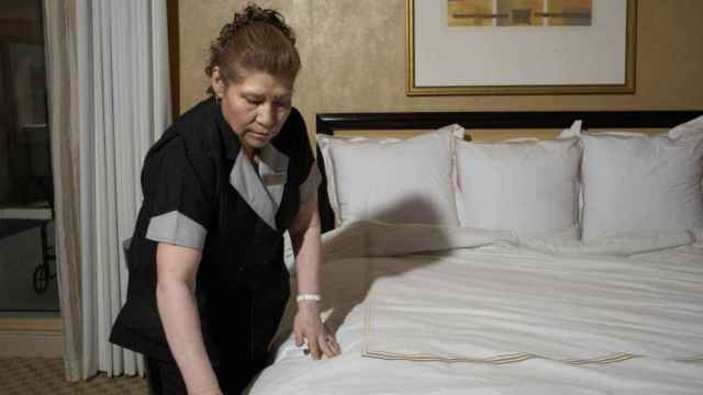 Una camarera de piso arregla una cama en un hotel.