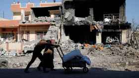 Dos hombres pasan por delante de un edificio destruido por los enfrentamientos en Mosul.