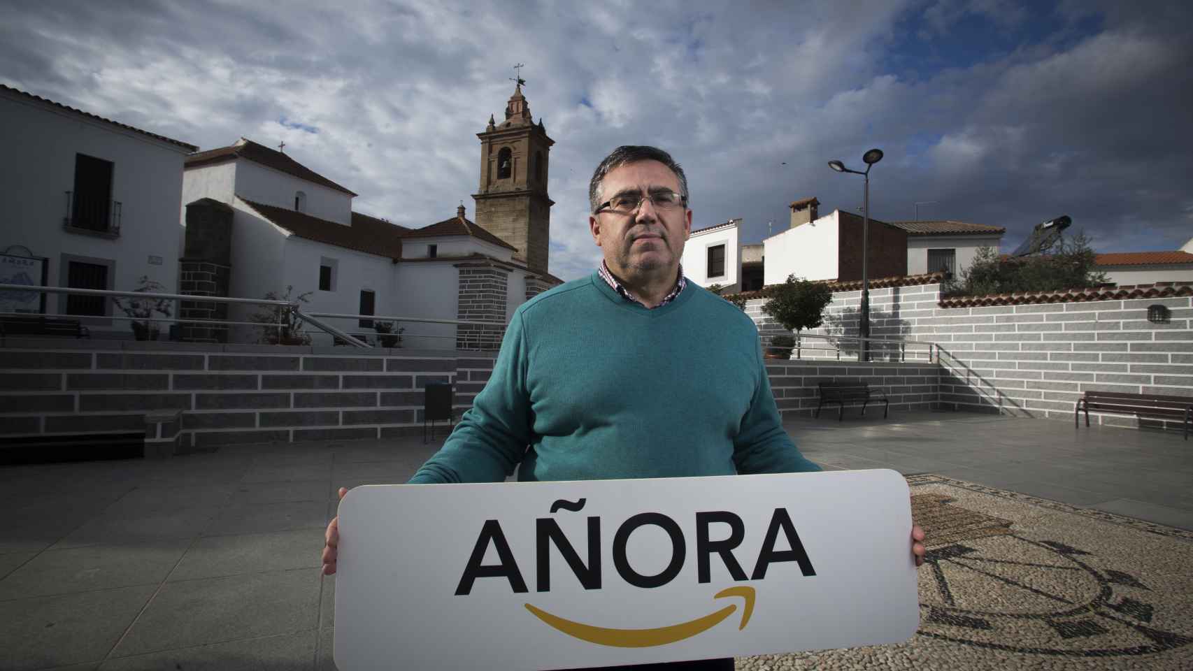 Bartolomé Madrid, alcalde de Añora, posa con el cartel que le regaló Amazon durante la visita que sus directivos hicieron al pueblo.