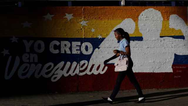 Mujer frente a un mural en apoyo al Gobierno en Caracas