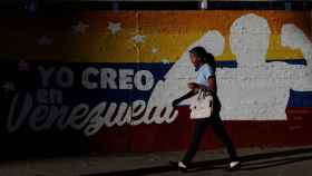 A Venezuelan woman walks past a mural with a graffiti that reads I believe in Venezuela in Caracas