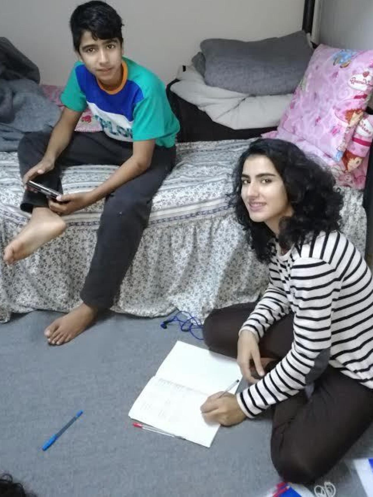 Sahar, con su hermano, no pierde la sonrisa en un campamento de refugiados de Grecia.