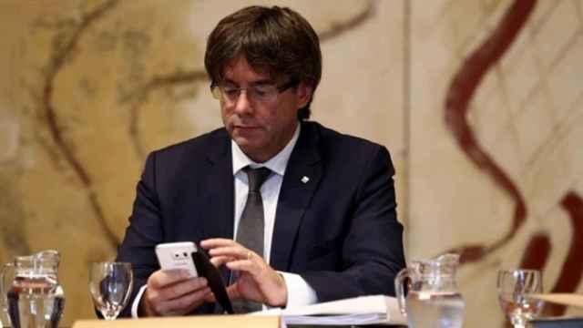El presidente de la Generalitat, Carles Puigdemont, consulta su teléfono móvil.