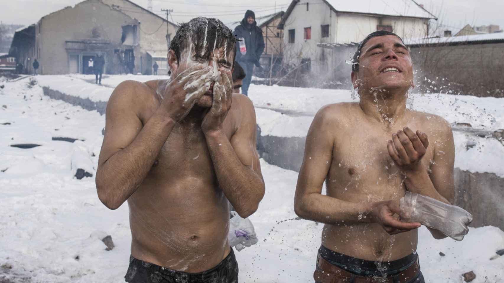 Dos jóvenes se bañan con agua calentada por una hoguera en el exterior de los almacenes a - 17º bajo cero, Belgrado, Serbia.