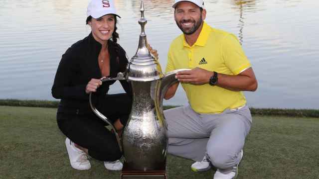 Angela Akins y Sergio García posan sonrientes junto al trofeo del golfista en Dubai.