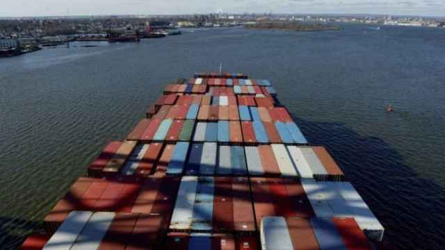 Un barco cargado de contenedores se dirige a un puerto para ser atendido por una empresa de estiba.