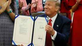 Trump muestra su firma estampada en la ley.