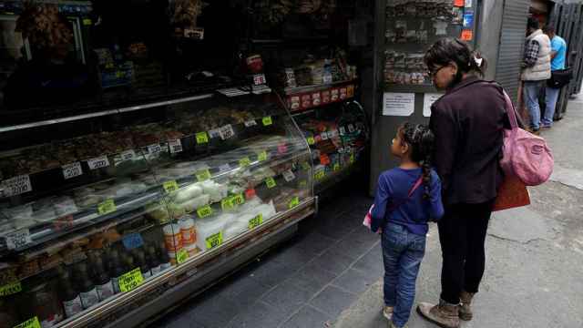 Una mujer y una niña pasan por delante de una tienda de comestibles en el centro de Caracas.
