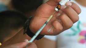 Un hombre prepara la inyección de una vacuna.