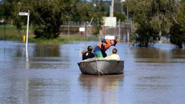 Una familia abandona su hogar en un bote atravesando la inundación