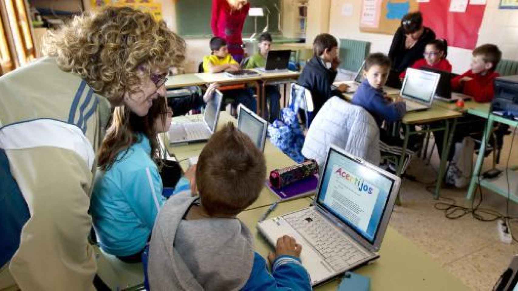 Varios niños en un aula con ordenadores.